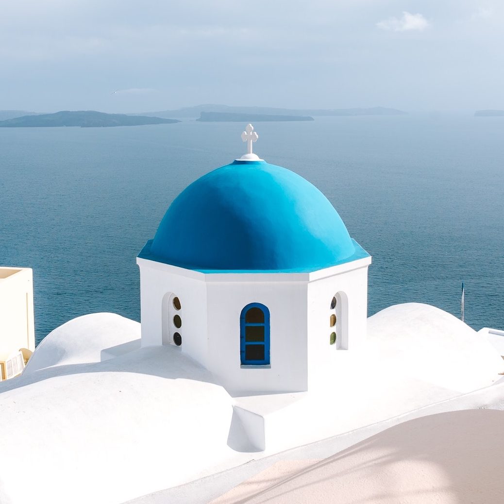 blue domed white building overlooking the sea in Greece