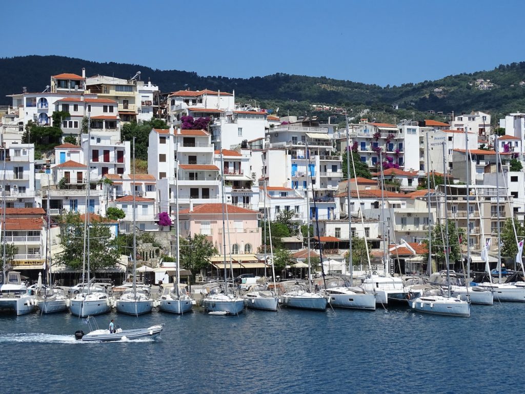 a line of white boats in front of white and brown buildings in Greece