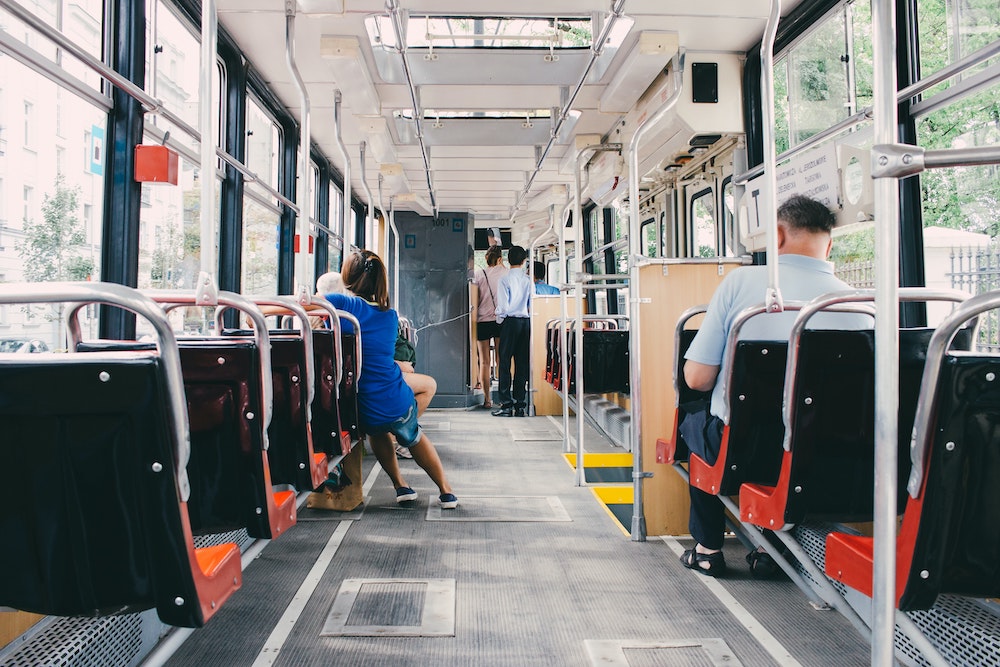 single file seats aboard an italian bus with three people sat down