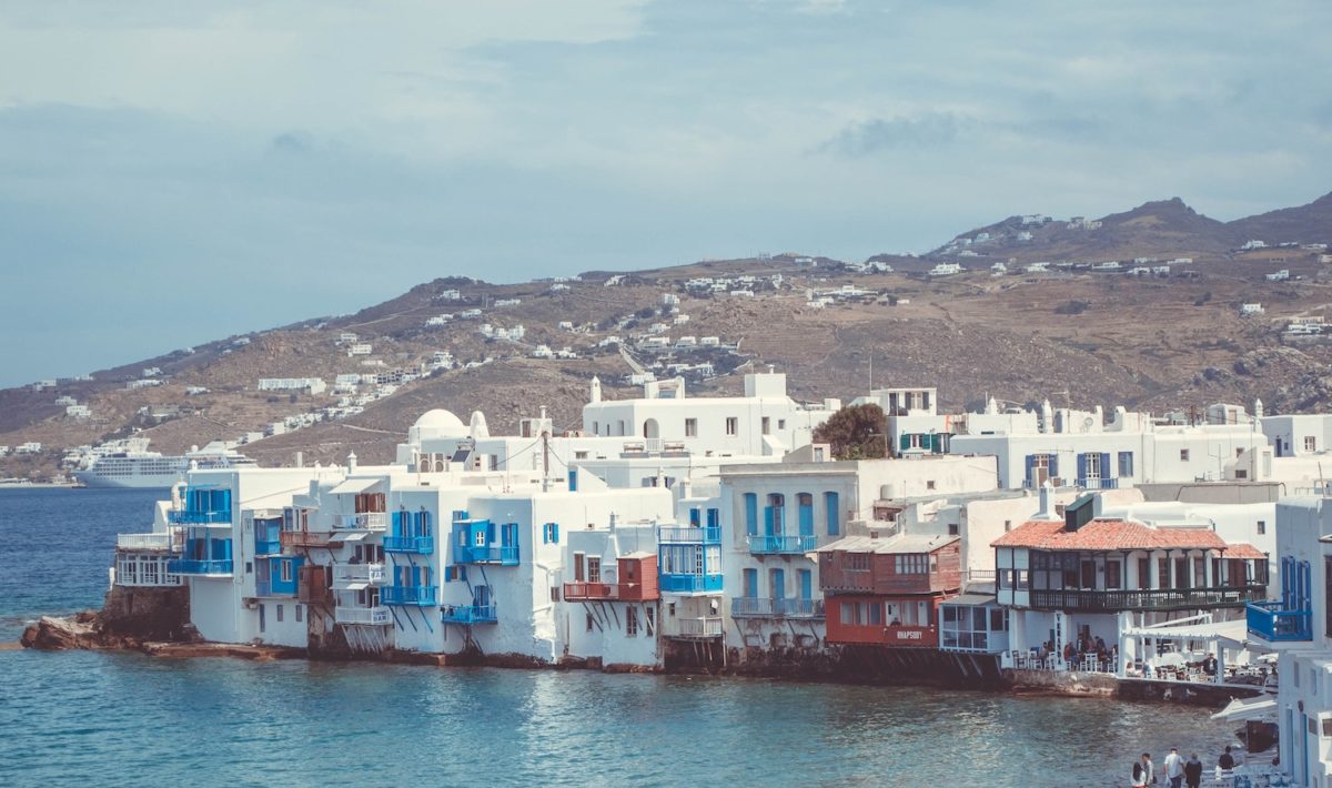 greek island, with direct flights from London, featuring white buildings with red and blue window shutters