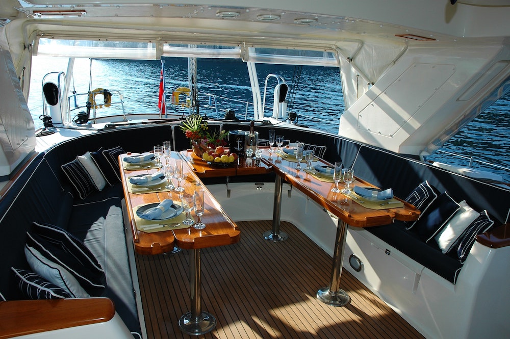 luxury yacht, U shaped dining table laid out with a selection of cutlery and glassware with a fruit bowl