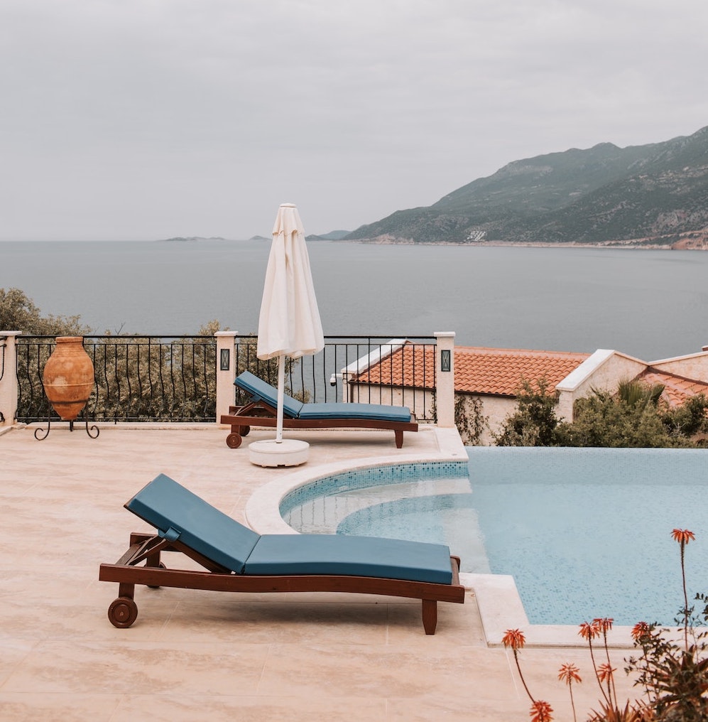 luxury greek villa pool side with blue sun loungers overlooking the sea