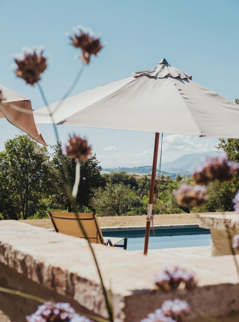 A parasol by a sunbed next to the private pool of an Italian villa 90 minutes from the airport with views of the countryside.