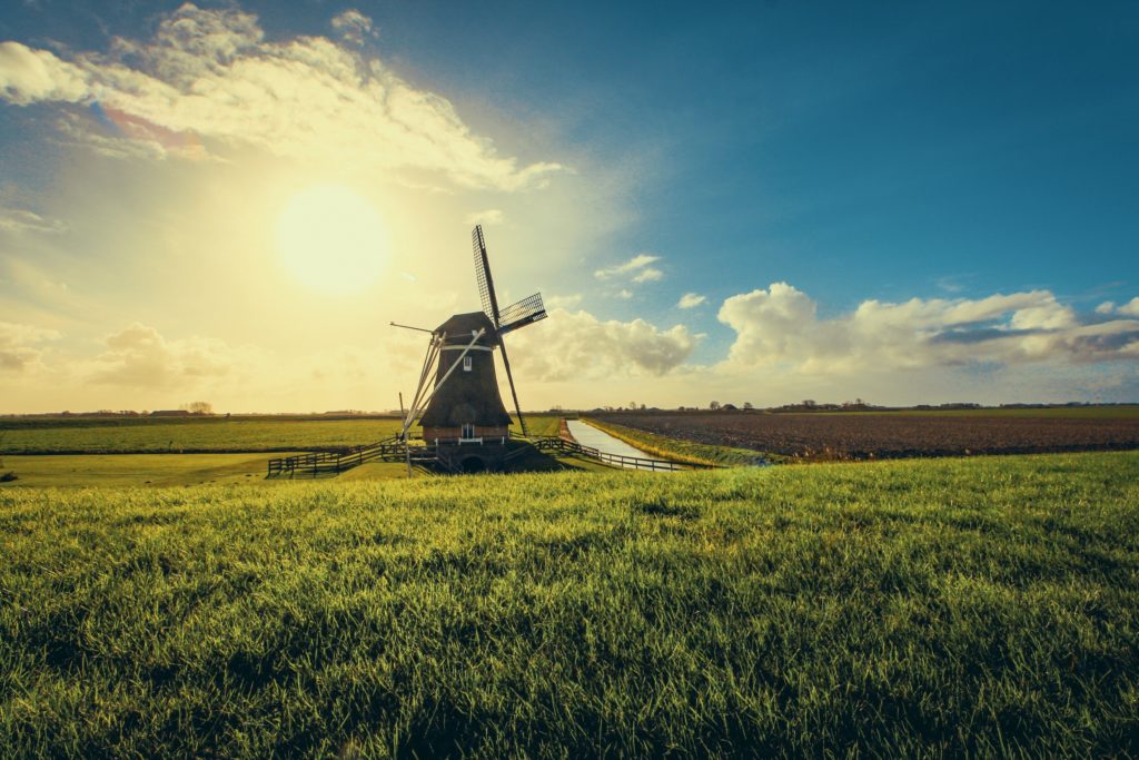 An iconic Netherlands windmill at sunset overlooking green landscape.