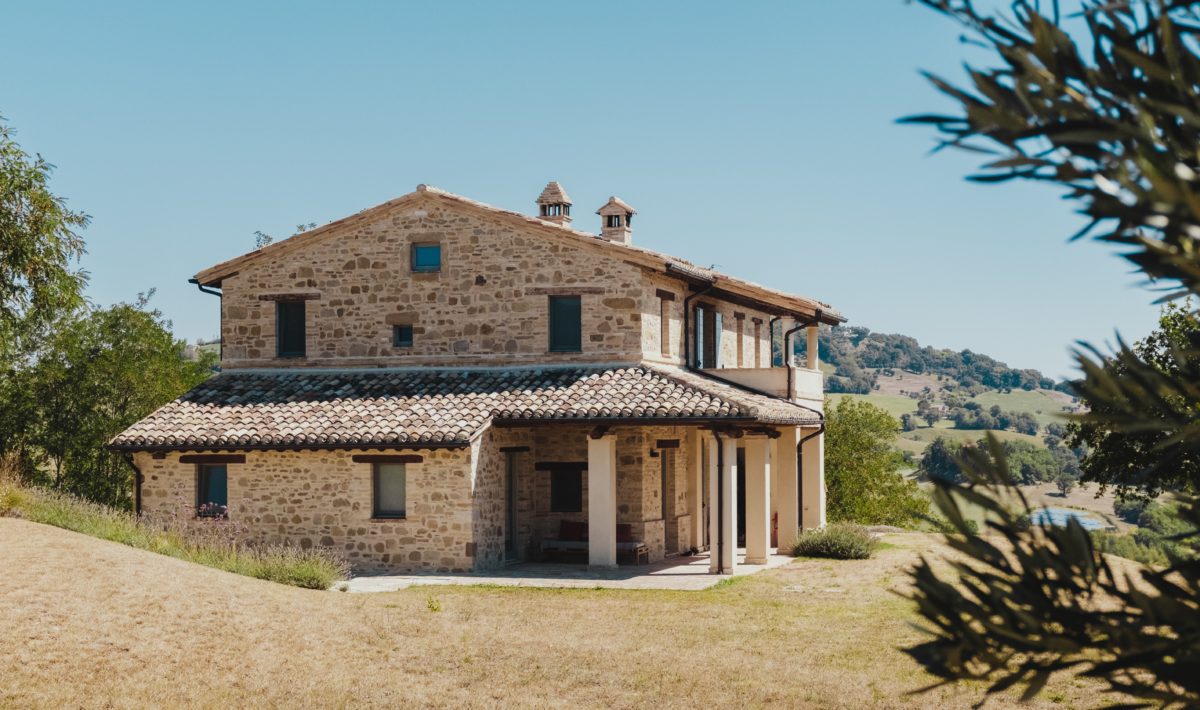 rustic Italian stone villa located on a green hill with bright blue skies
