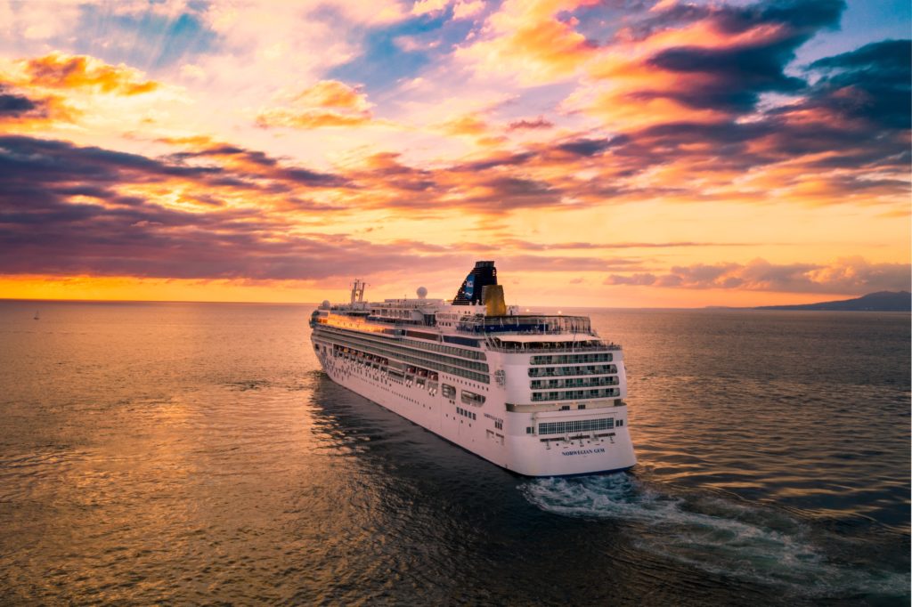 Booking a cruise example of a white luxury cruise ship in the open sea at sunset.