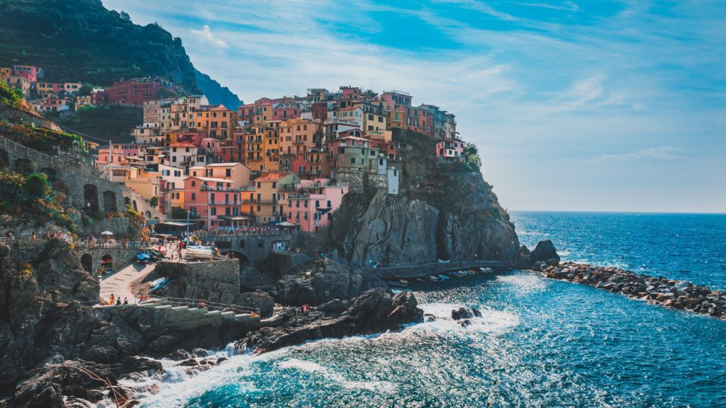 Colourful Italian houses built upon a cliff overlooking the sparkling blue sea.